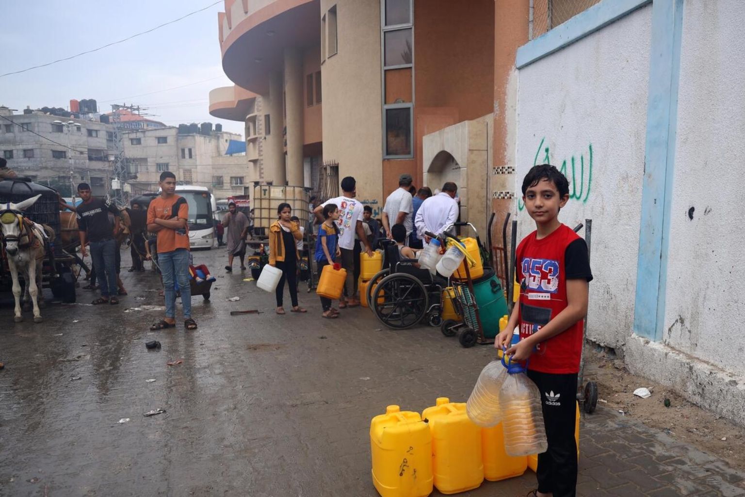 Ahmad de 14 años, espera en la línea de agua potable en la ciudad de Rafah, Ahmad evacuó su casa en Jabalia tras la guerra.